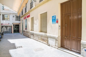 A building with a closed shuttered entrance, a sign for 'RENTALS MADRID', and a blue 'AT' sign indicating a business or service.