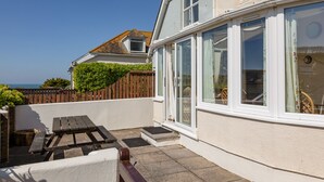 A coastal house with a patio, a wooden fence, and a view of the sea. - Cottage View (Kingsbridge)