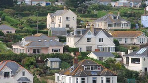 A residential area with houses featuring pitched roofs, some with solar panels, surrounded by greenery and a field in the background. - Cottage View (Kingsbridge)