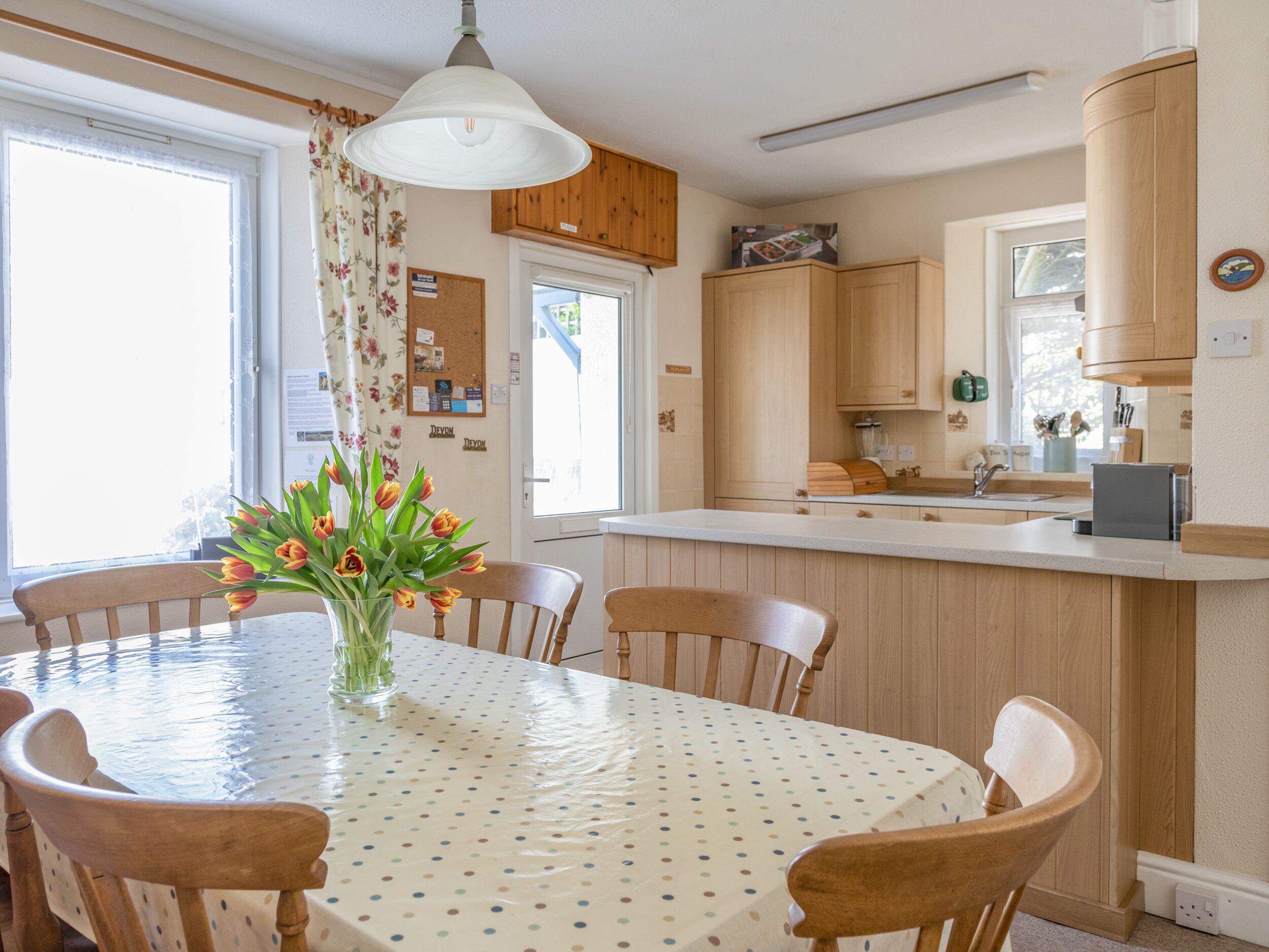 A kitchen with wooden cabinets, a white countertop, and a dining table with chairs.