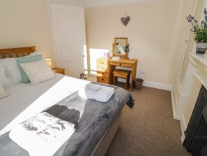 A bedroom with a bed, a wooden dresser, a mirror, and a small potted plant. - 5 Albany Road (Stratford-upon-Avon)