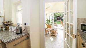 A kitchen with granite countertops, a toaster, and a window. There is a door leading to a patio with outdoor furniture and a garden.
