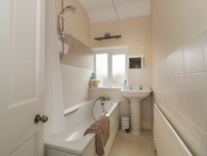 A bathroom with a bathtub, a sink, and a window. - 5 Albany Road (Stratford-upon-Avon)