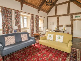 A room with two sofas, a patterned carpet, and a wooden ceiling.