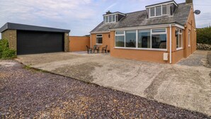 A residential property with a garage, a patio with chairs, and a large windowed room.