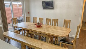Un comedor con una mesa y sillas de madera, un banco y un cuenco rojo pequeño con adornos.