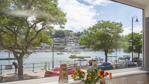 A table set with wine glasses and a bottle, overlooking a marina with boats and a cityscape. - Leeside (Dartmouth)
