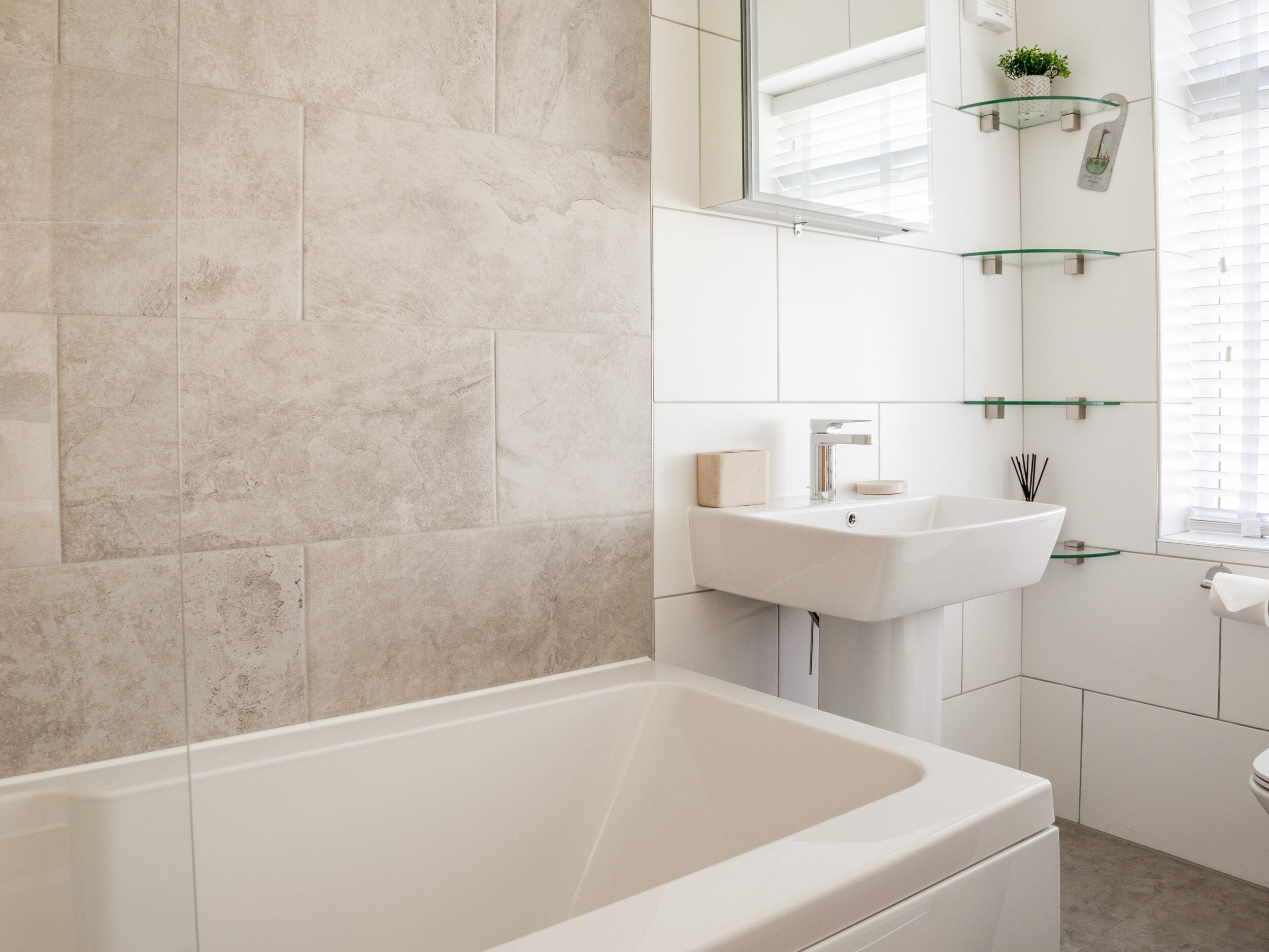 A modern bathroom with a bathtub, a sink, and a mirror.
