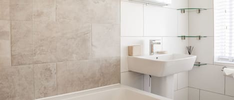 A modern bathroom with a bathtub, a sink, and a mirror.