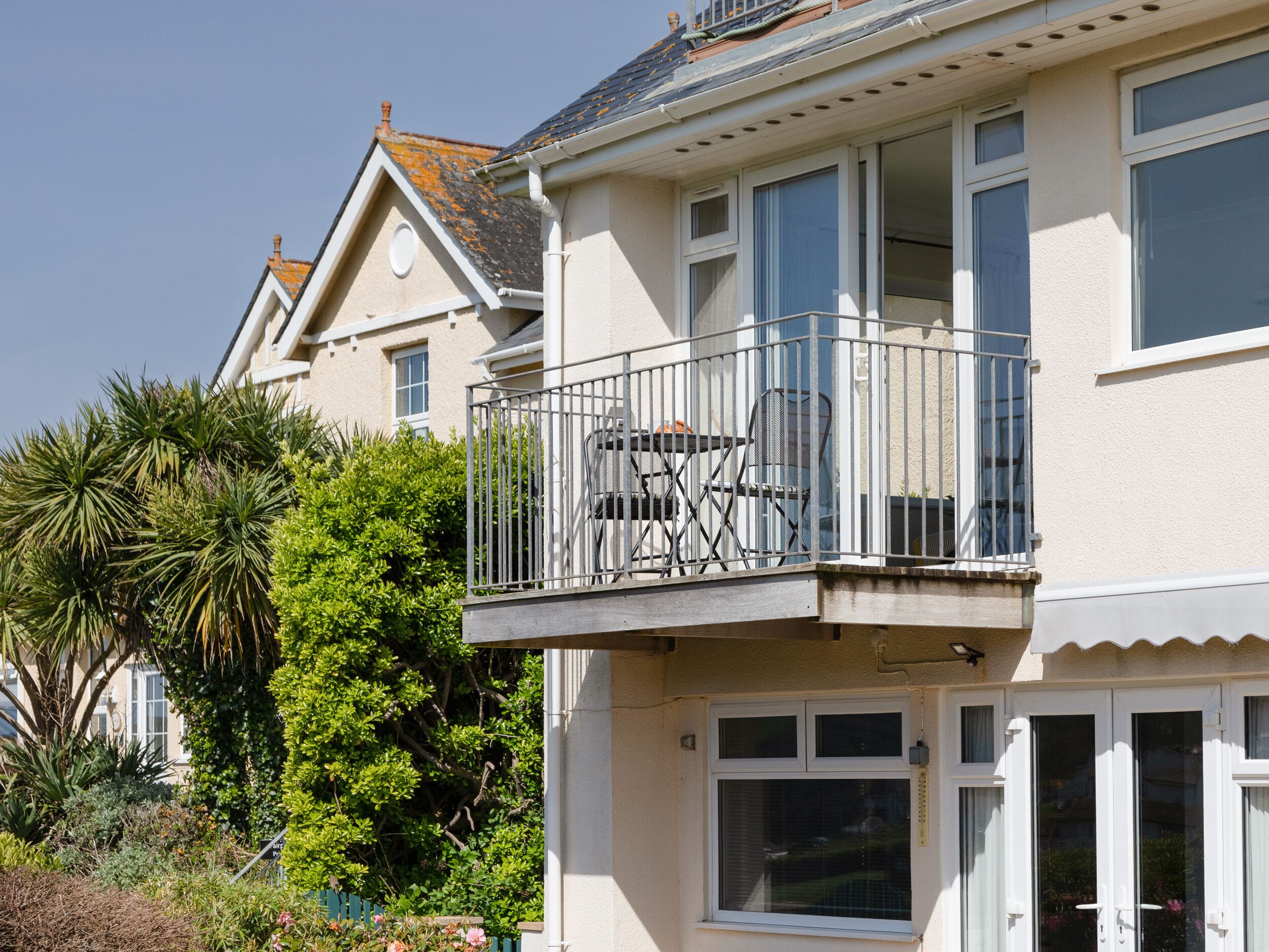 A two-story house with a balcony featuring outdoor furniture.