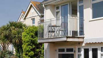 A two-story house with a balcony featuring outdoor furniture.