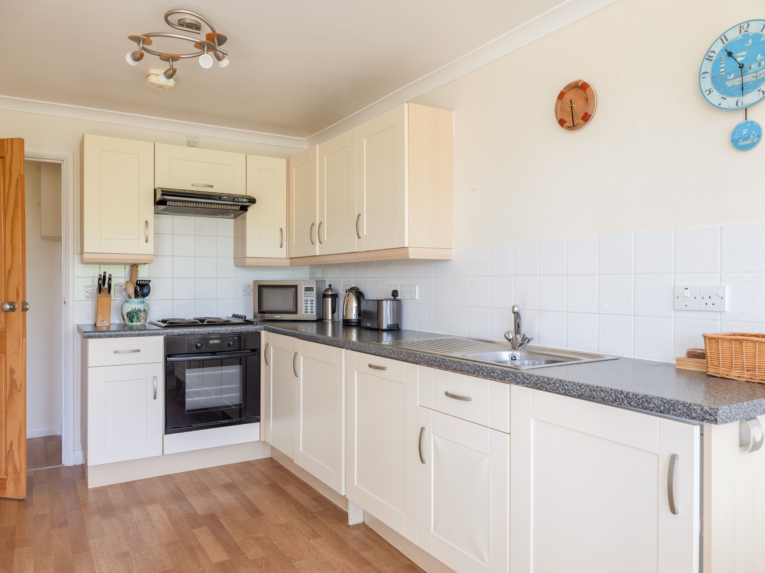 A modern kitchen with white cabinets, a microwave, a stove, and a sink.