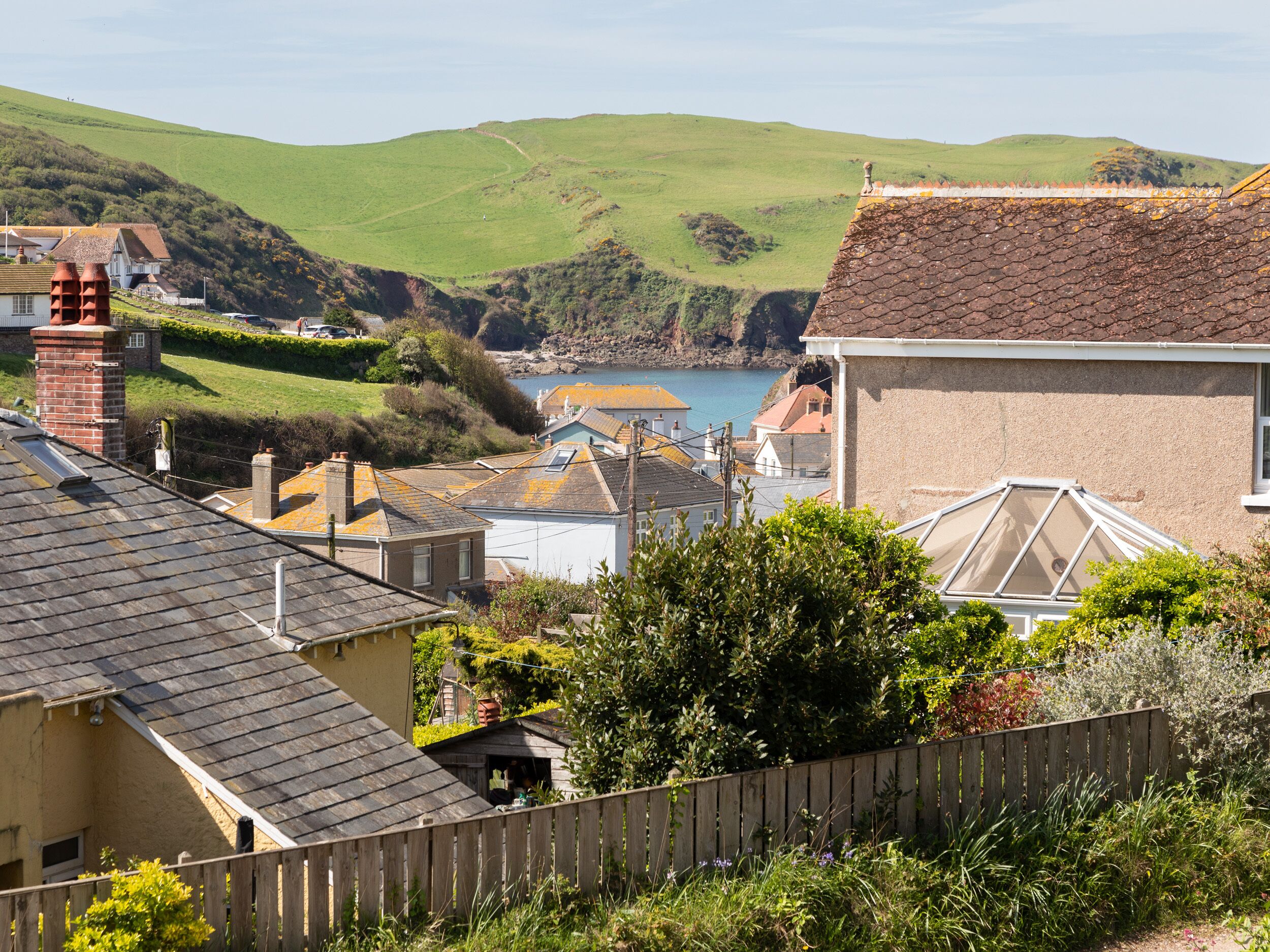 A coastal village with houses, a wooden fence, and a view of the sea.