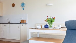A modern kitchen with white cabinets, a wooden countertop, and a dining table with a vase of tulips. - Grand View (Kingsbridge)