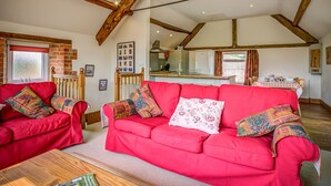 A cozy living room with a red sofa set, a wooden coffee table, and exposed wooden beams on the ceiling. - Top Barn (Shipston on Stour)