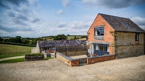 A two-story stone house with a sloped roof, a large window, and a gravel driveway. - Top Barn (Shipston on Stour)