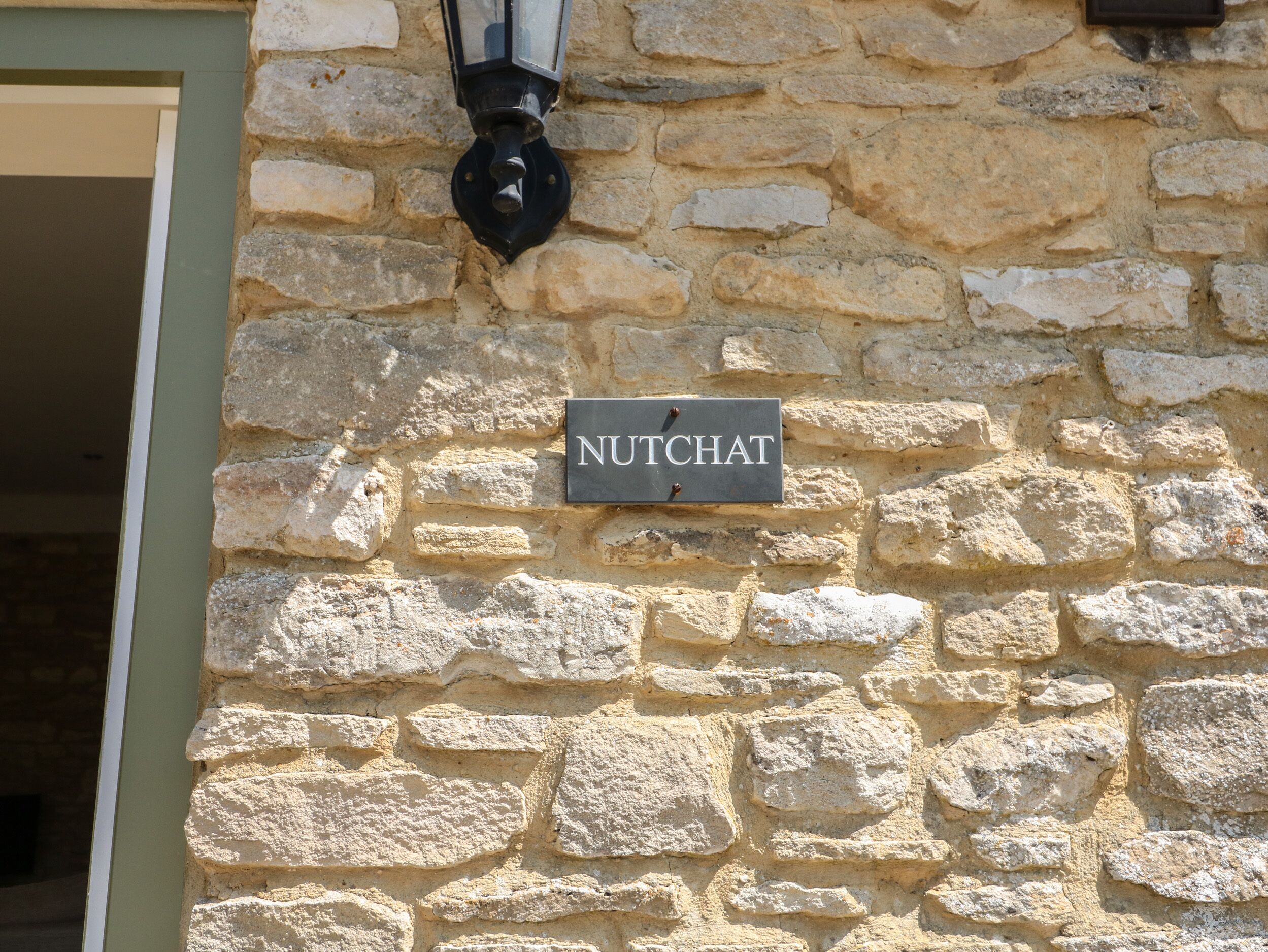 A stone wall with a sign reading "NUTCHAT".