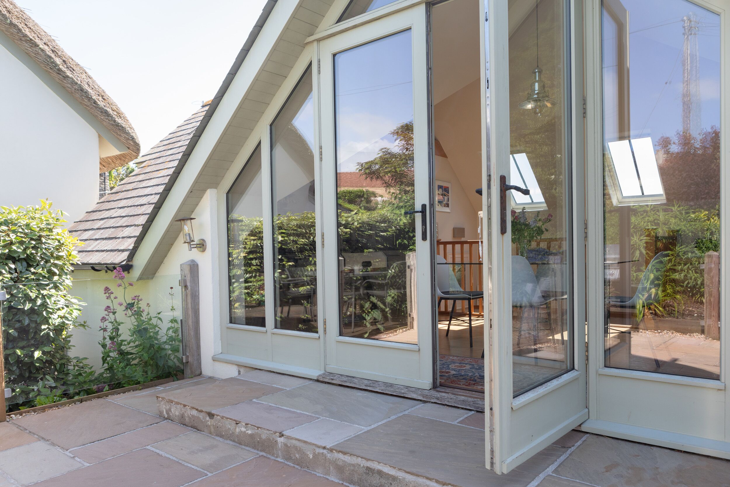 A house with a sliding glass door leading to a patio area with a table and chairs.