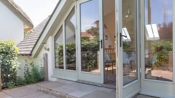 A house with a sliding glass door leading to a patio area with a table and chairs.