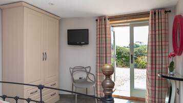 A bedroom with a bed, a wardrobe, a television, a chair, and a view of the outdoors.