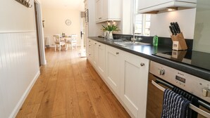 A modern kitchen with white cabinets, a black countertop, and a built-in oven. - Ewecub Barn (Witney)