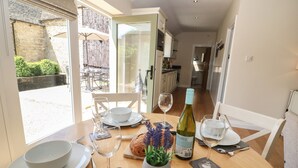 A dining table set for two with a bottle of wine, a bowl, and cutlery. - Ewecub Barn (Witney)