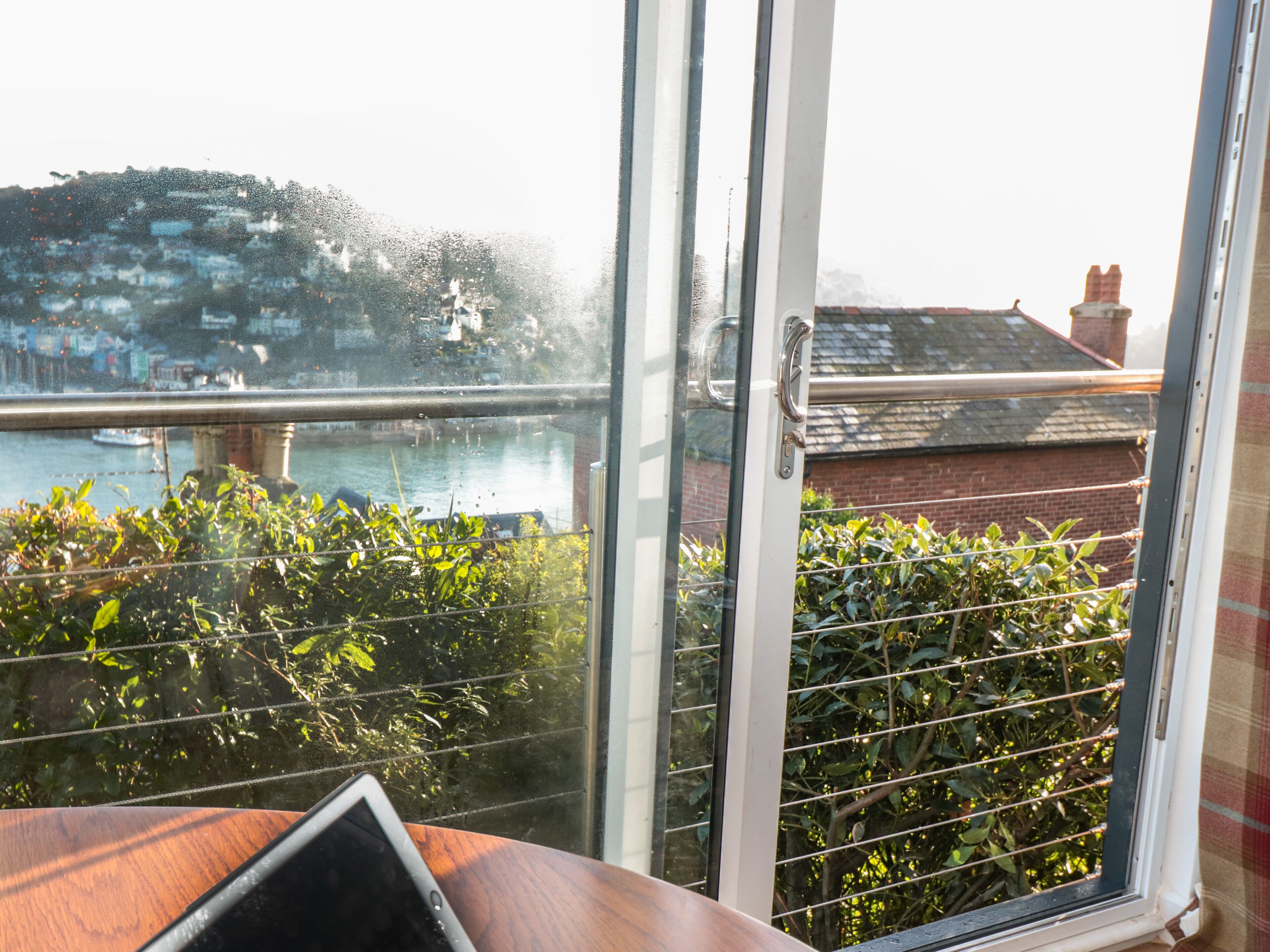 A view from a window with a metal grill, overlooking a body of water and buildings.