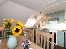 Una cocina con armarios color turquesa, una mesa de comedor de madera con un jarrón de girasoles y una estufa.