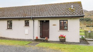 A single-story building with a tiled roof, a front door, and two windows. - Church House (Achnasheen)