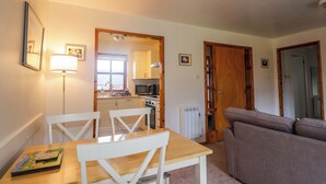 A compact living space with a dining table, chairs, a sofa, and a kitchenette. - Church House (Achnasheen)