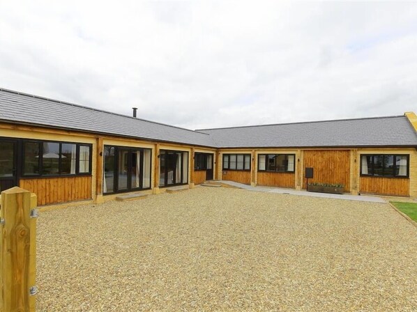 A building with a gravel courtyard, wooden exterior walls, and large windows.