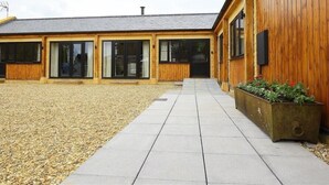 Un bâtiment à l’extérieur en bois, doté de grandes fenêtres et d’une cour recouverte de gravier.