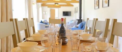 A dining table set with white plates, bowls, and wine glasses, with a bottle of wine in the center.
