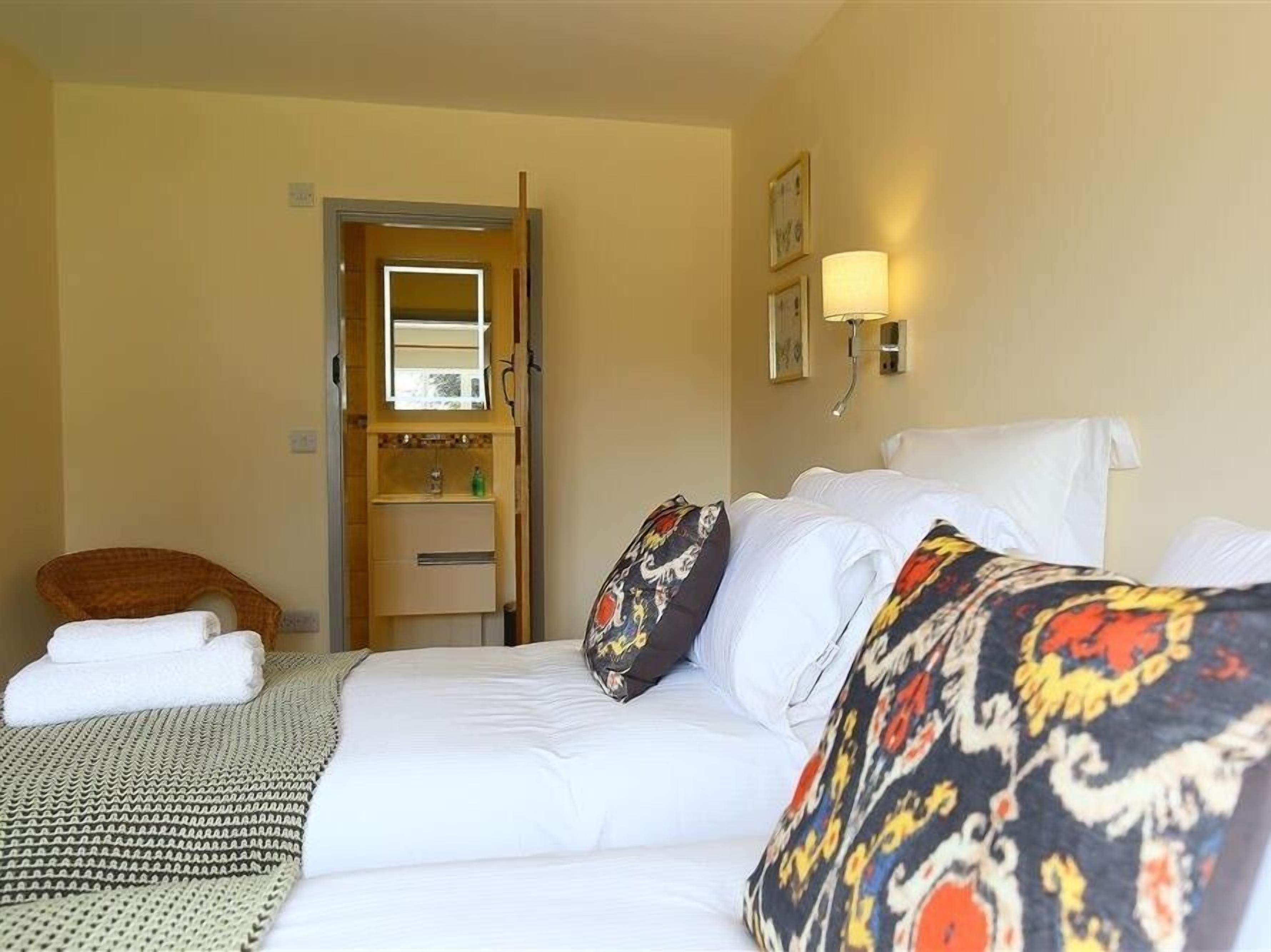 A hotel room with a bed, a chair, a small table, and a door leading to a bathroom.