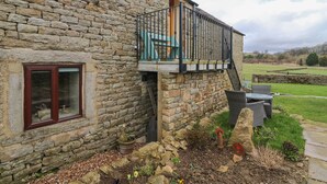 Ein Gebäude aus Stein mit Balkon, Fenster und Gartenanlage mit Pflanzen und einer Steinmauer.