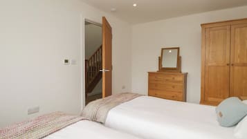 A bedroom with two beds, a wooden wardrobe, a dresser, and a mirror.
