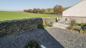 A stone wall, a gravel path, and a building with a white exterior. - Yew Fold (Kirkby-in-Furness)