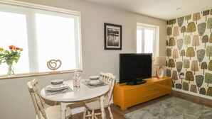 A dining area with a round table, chairs, a television, and a cabinet. - Yew Fold (Kirkby-in-Furness)