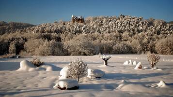 A snow-covered landscape with a house on a hill.