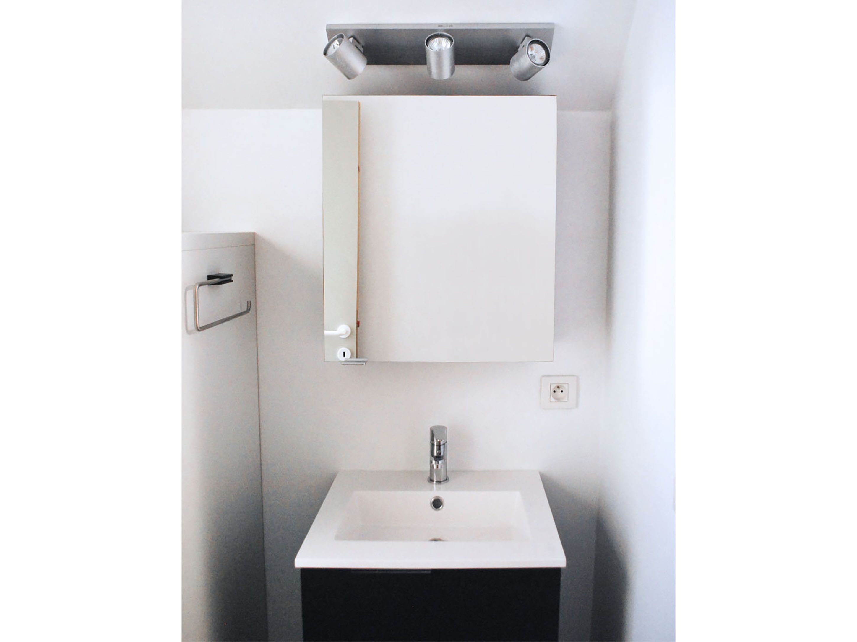 A bathroom with a white sink, a mirror, and a towel rack.