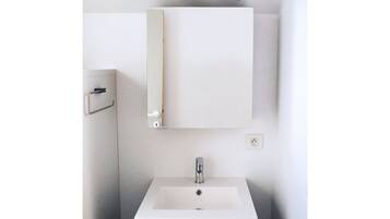 A bathroom with a white sink, a mirror, and a towel rack.