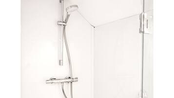 Een douche met een handdouche en een bedieningspaneel aan de muur.