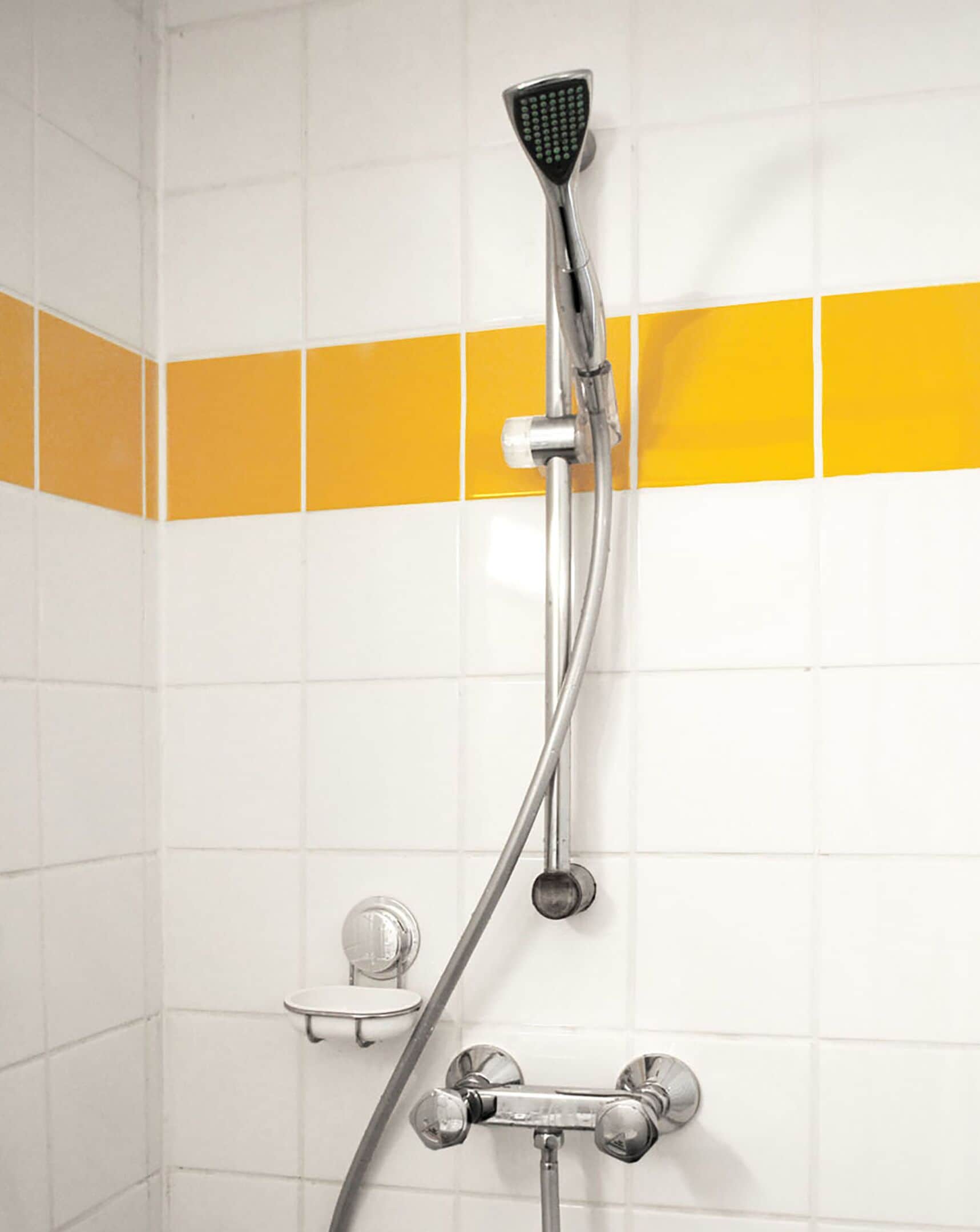 A shower with a handheld showerhead and a wall-mounted faucet.