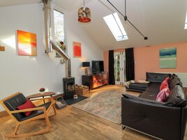 Una sala moderna con chimenea, un sofá, un sillón y una televisión.