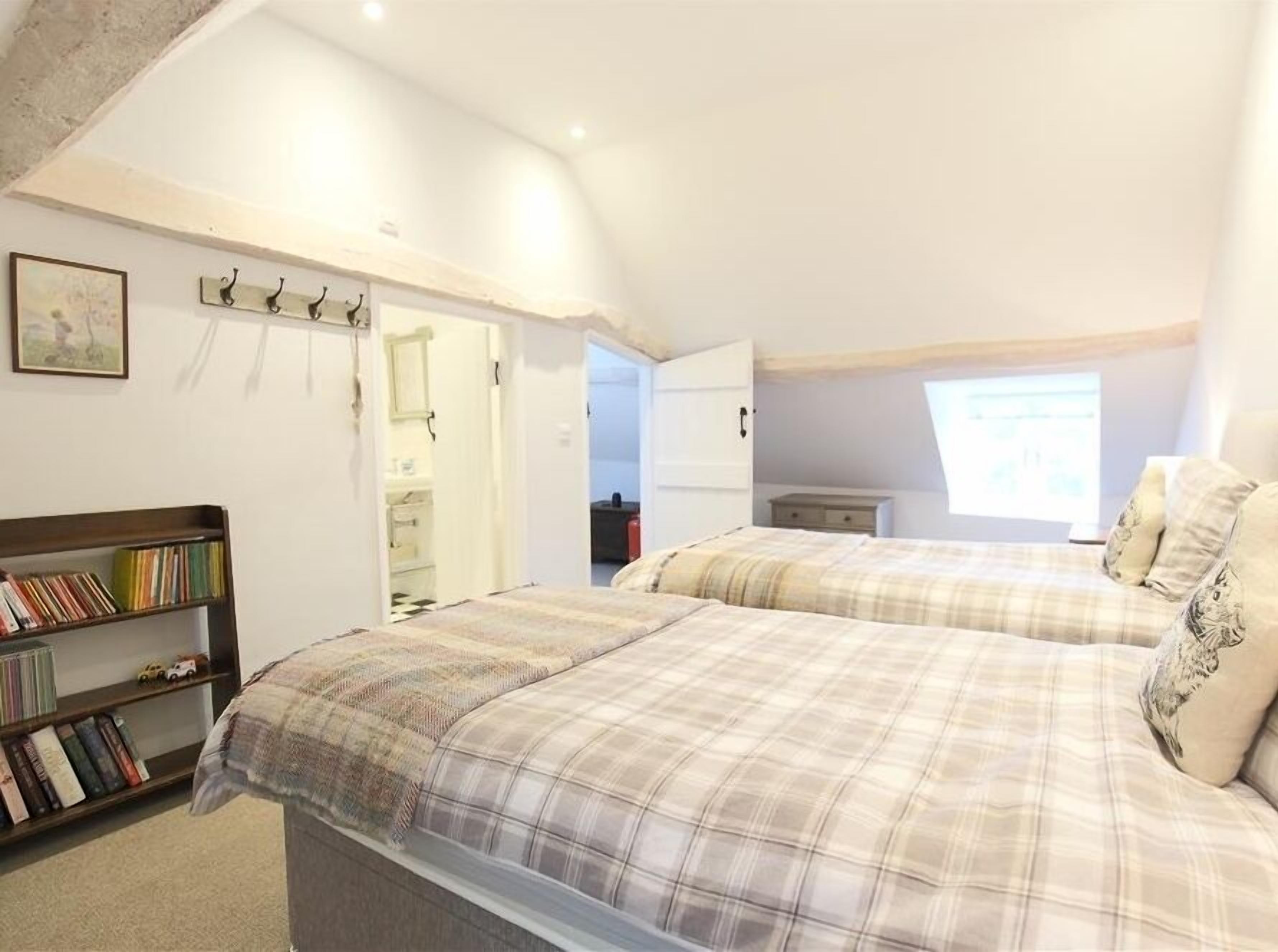 Un dormitorio con dos camas, una estantería, un armario y una ventana.