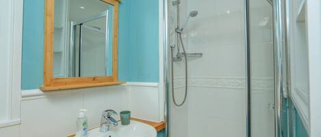 A bathroom with a sink, mirror, and shower.
