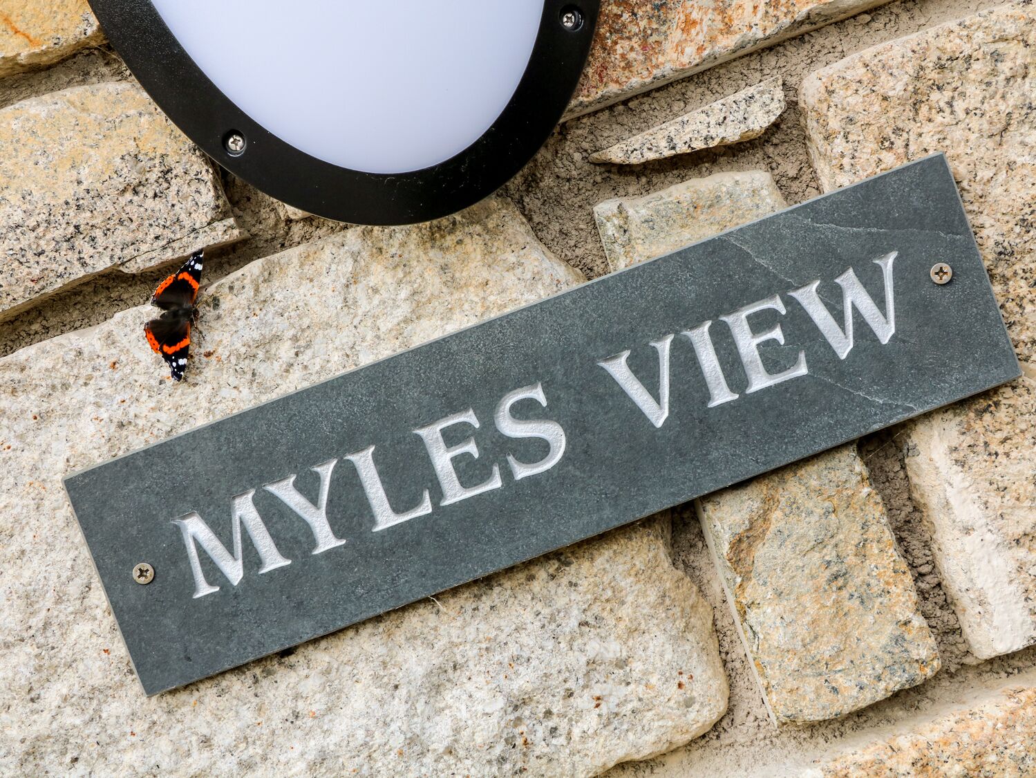 A stone sign with the inscription "MYLES VIEW" mounted on a stone wall.