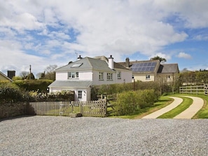 A two-story house with a gravel driveway and a wooden fence.