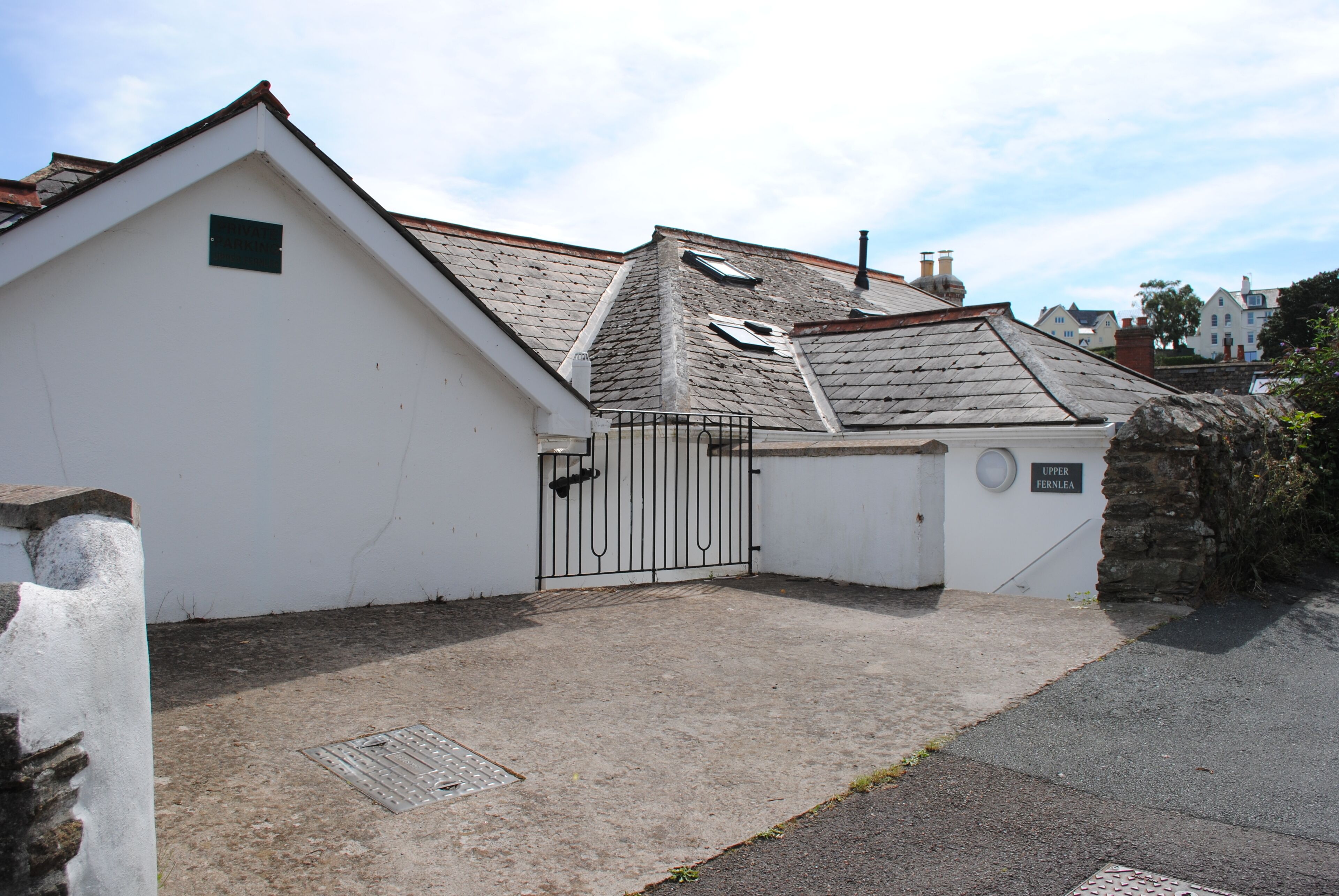 A white building with a sloped roof and a metal gate.