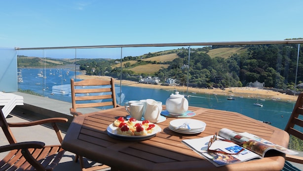 A table with a view of a coastal area, including boats and hills. - 2 Poundstone Court (Salcombe)